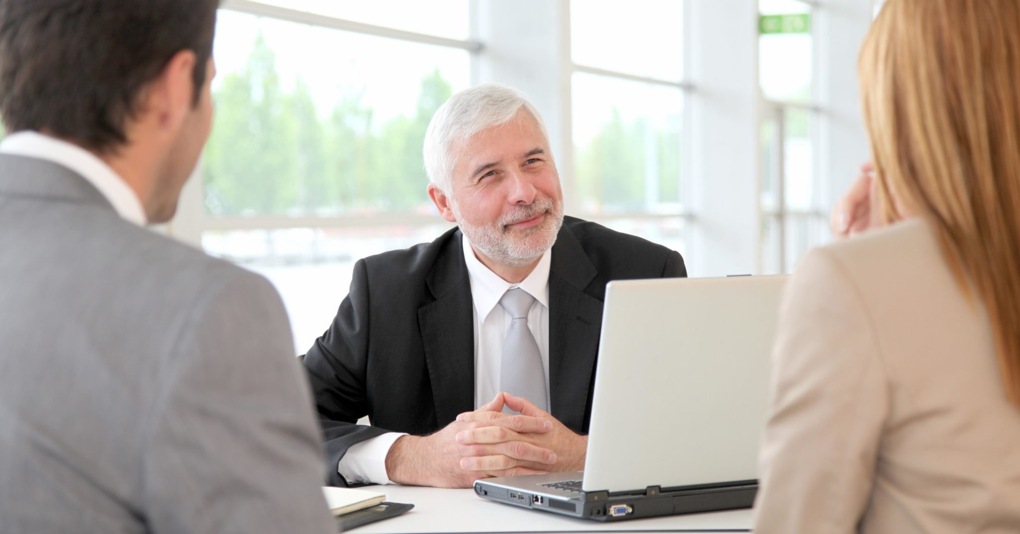 Business man sitting at desk in a B2B sales meeting facing two clients