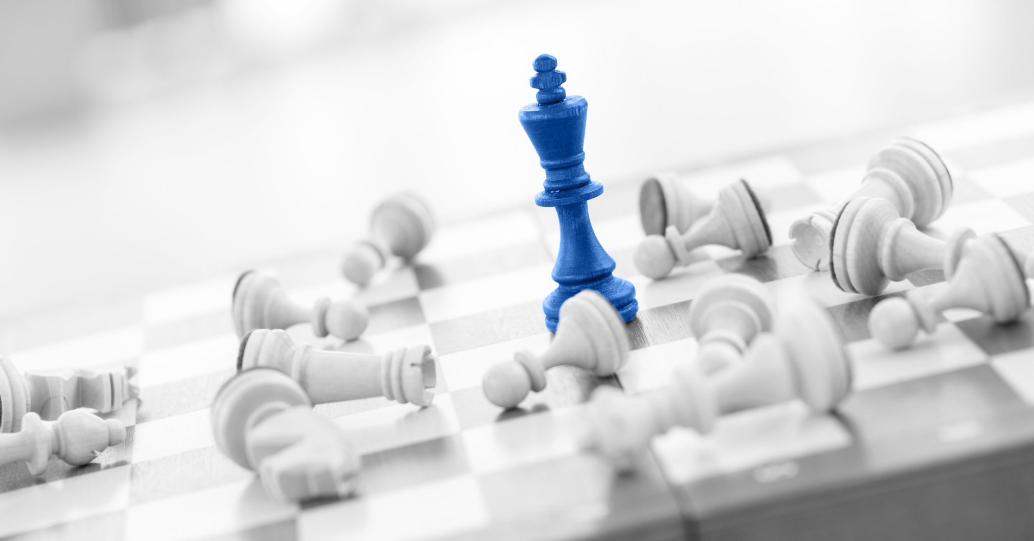Chess board with one blue chess piece representing business innovation left standing and all white pieces knocked down