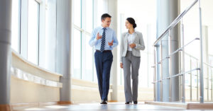 A marketing officer and other business executive walking down a hallway strategizing.