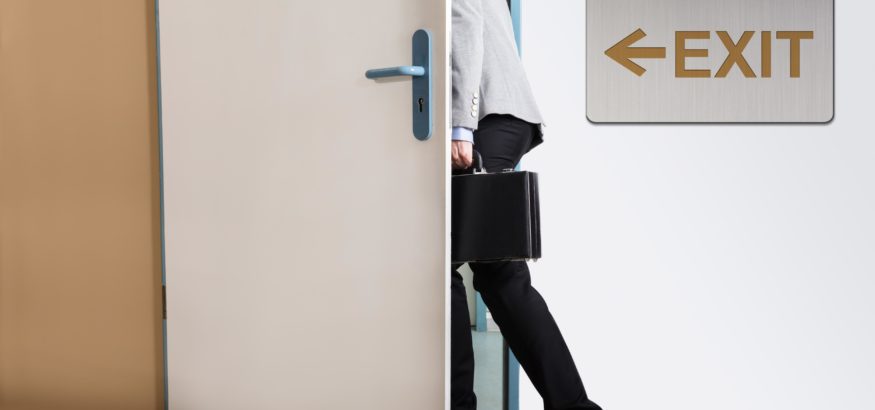 Business man exiting a door with brief case in hand.