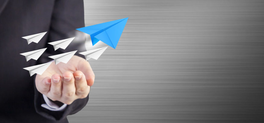 Man holding paper airplanes as a sign of leadership goals as they fly out of his hand